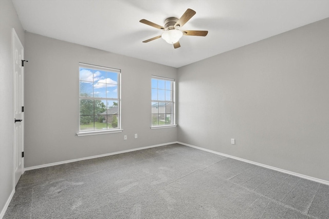 carpeted empty room with ceiling fan and baseboards