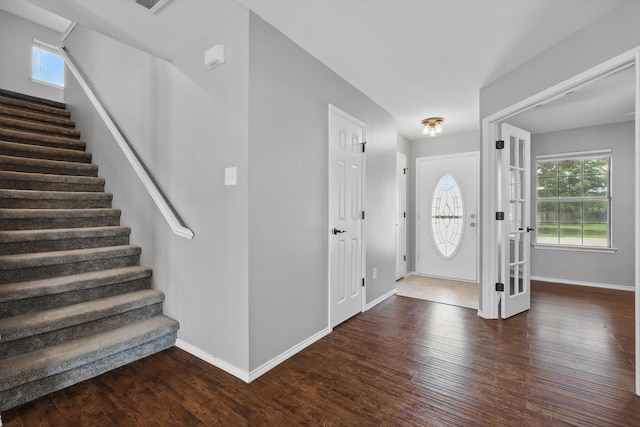 foyer entrance with stairs, wood finished floors, and baseboards