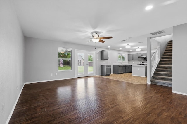 unfurnished living room featuring a ceiling fan, baseboards, wood finished floors, stairs, and recessed lighting