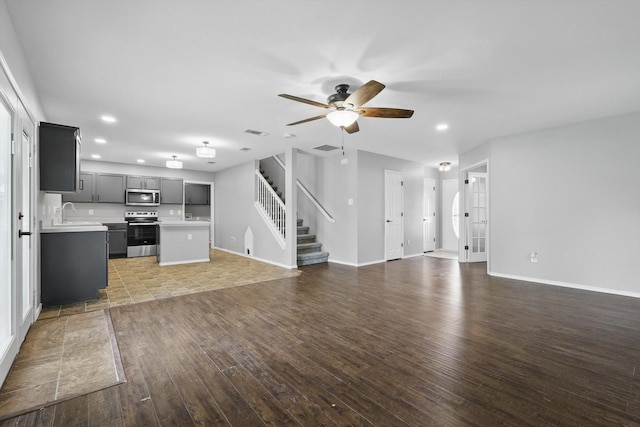 unfurnished living room with ceiling fan, wood-type flooring, stairs, recessed lighting, and baseboards