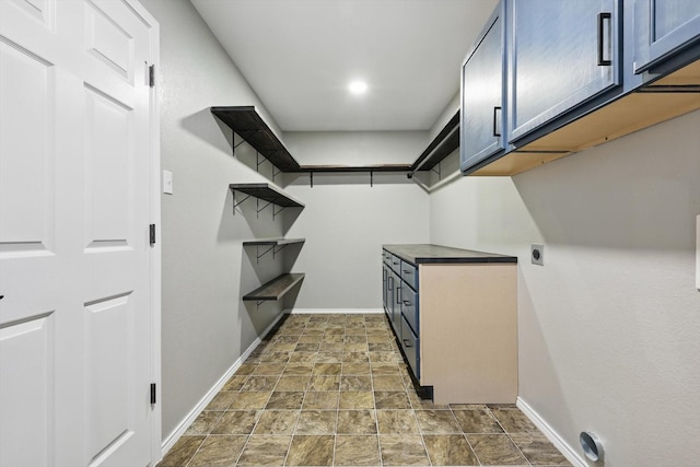 laundry room featuring baseboards, dark stone finish flooring, hookup for an electric dryer, and cabinet space