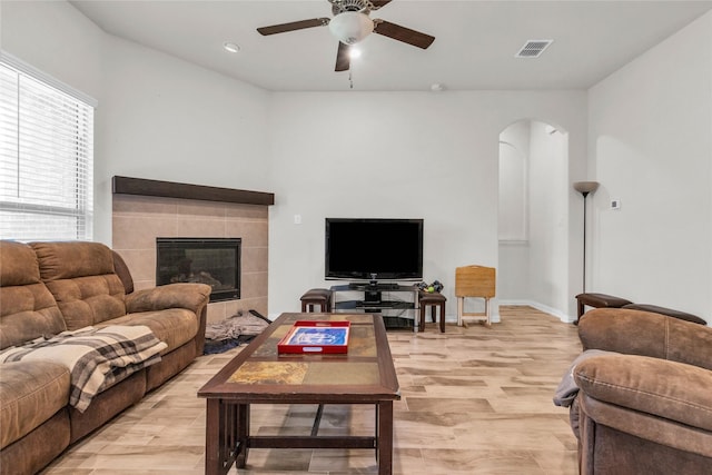 7225 Tesoro Trl, Fort Worth, TX 76131 - living room featuring arched walkways, a ceiling fan, a tile fireplace, baseboards, and light wood-style floors