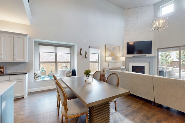 16175 Barton Creek Ln, Frisco, TX 75033 - dining area with a towering ceiling, a glass covered fireplace, dark wood-style floors, healthy amount of natural light, and a chandelier