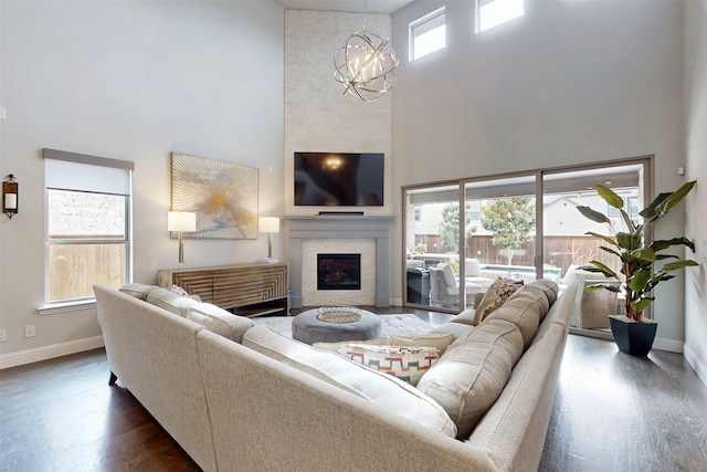 16175 Barton Creek Ln, Frisco, TX 75033 - living area featuring a towering ceiling, baseboards, a chandelier, dark wood-style floors, and a glass covered fireplace