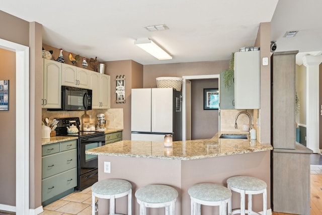 kitchen featuring black appliances, a peninsula, tasteful backsplash, and a sink