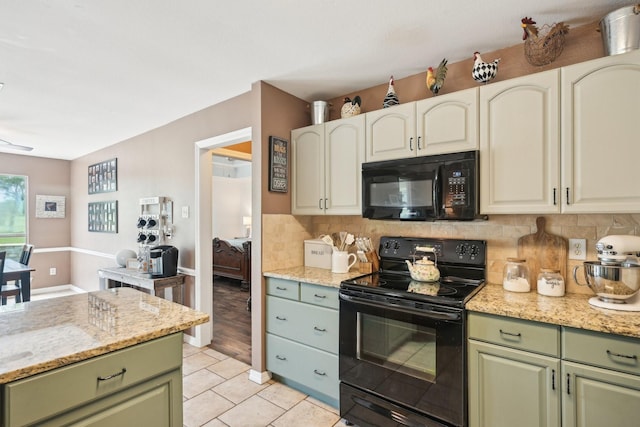kitchen featuring black appliances, green cabinets, backsplash, and light stone counters