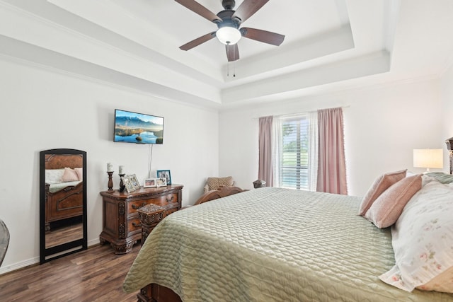 bedroom featuring a raised ceiling, dark wood finished floors, baseboards, ceiling fan, and crown molding