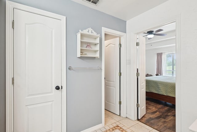 hall featuring light tile patterned flooring and baseboards