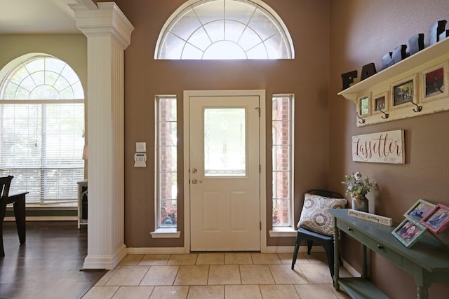 entryway featuring decorative columns, baseboards, and light tile patterned floors