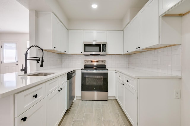 22 W Mountain Ln Unit 42, Grand Prairie, TX 75052 - kitchen featuring appliances with stainless steel finishes, a sink, light countertops, white cabinetry, and decorative backsplash