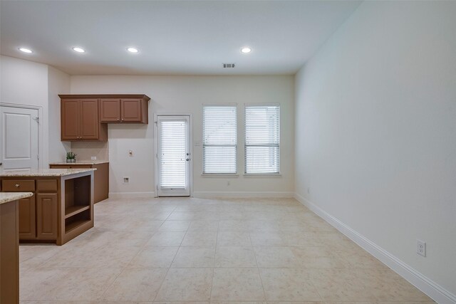 15429 Pioneer Bluff Trl, Fort Worth, TX 76262 - kitchen with open shelves, recessed lighting, light stone countertops, baseboards, and brown cabinets