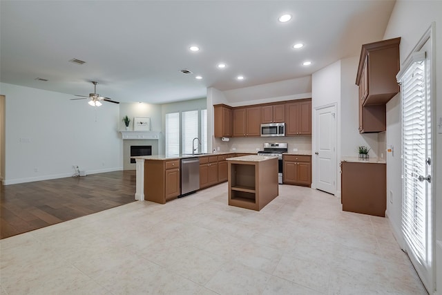 15429 Pioneer Bluff Trl, Fort Worth, TX 76262 - kitchen featuring stainless steel appliances, open floor plan, a ceiling fan, a center island, and a fireplace