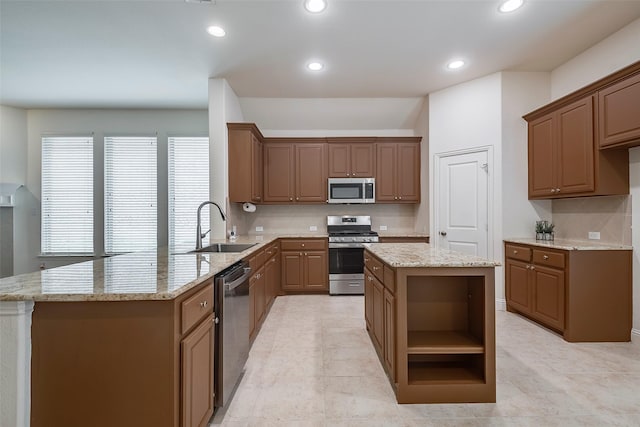 15429 Pioneer Bluff Trl, Fort Worth, TX 76262 - kitchen featuring appliances with stainless steel finishes, a sink, a peninsula, decorative backsplash, and light stone countertops