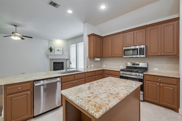 15429 Pioneer Bluff Trl, Fort Worth, TX 76262 - kitchen with appliances with stainless steel finishes, a sink, a ceiling fan, tasteful backsplash, and a peninsula