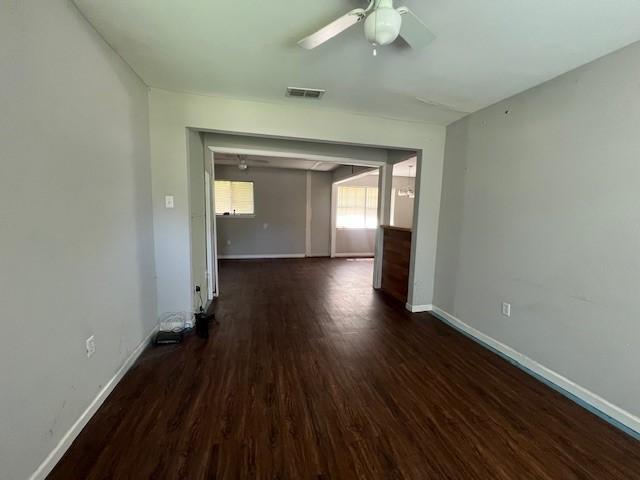 unfurnished room with a ceiling fan, dark wood finished floors, and baseboards