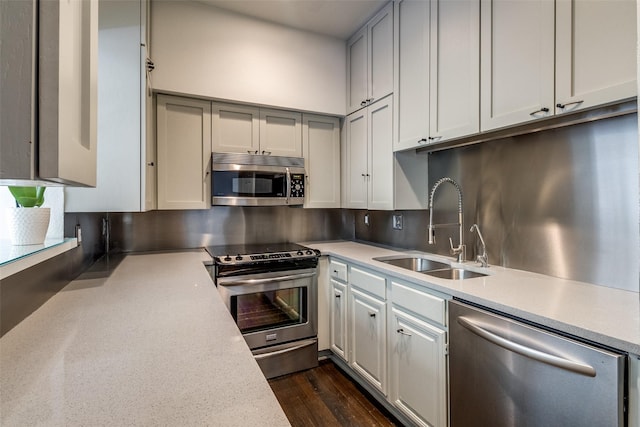 kitchen with stainless steel appliances, a sink, light countertops, and dark wood-style floors