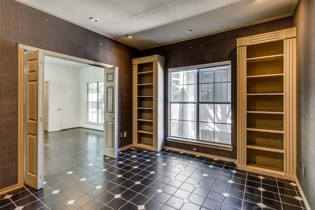 spare room with baseboards, dark tile patterned floors, and built in shelves