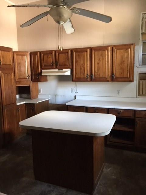 211 N Pleasant St, Hillsboro, TX 76645 - kitchen featuring brown cabinets, under cabinet range hood, and a ceiling fan