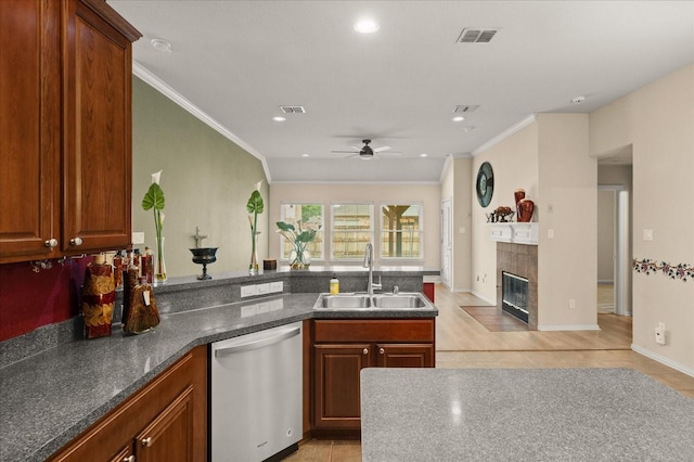 kitchen with a sink, stainless steel dishwasher, ornamental molding, ceiling fan, and a fireplace