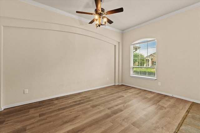 spare room featuring wood finished floors, crown molding, ceiling fan, and baseboards