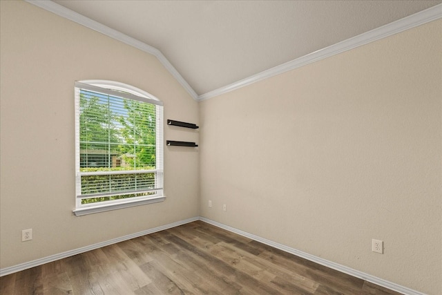 empty room featuring crown molding, wood finished floors, baseboards, and vaulted ceiling
