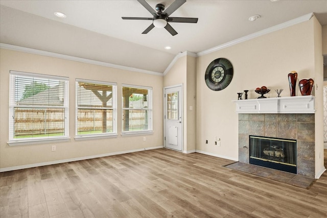 unfurnished living room featuring healthy amount of natural light, a tiled fireplace, lofted ceiling, a ceiling fan, and wood finished floors