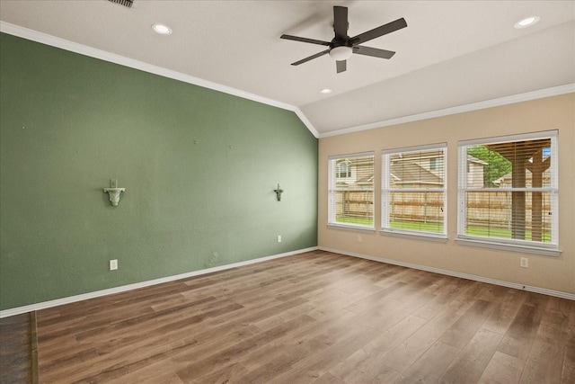 spare room featuring ornamental molding, lofted ceiling, a ceiling fan, wood finished floors, and baseboards