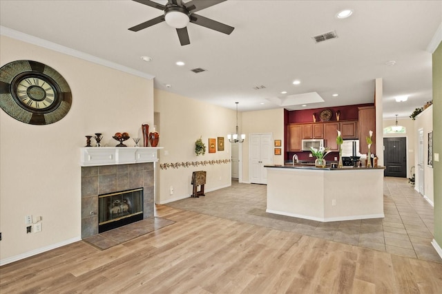 living room featuring recessed lighting, light wood finished floors, a tile fireplace, ceiling fan, and baseboards