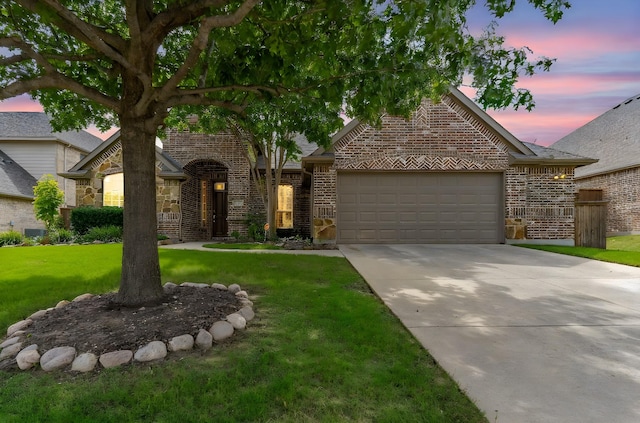 view of front facade featuring brick siding, a garage, a front yard, and concrete driveway