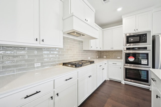 4190 Holland Ct, Prosper, TX 75078 - kitchen with stainless steel appliances, light countertops, white cabinets, decorative backsplash, and dark wood-style flooring