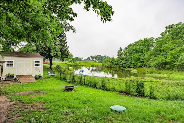 view of yard featuring a fire pit, a water view, a storage shed, and an outbuilding