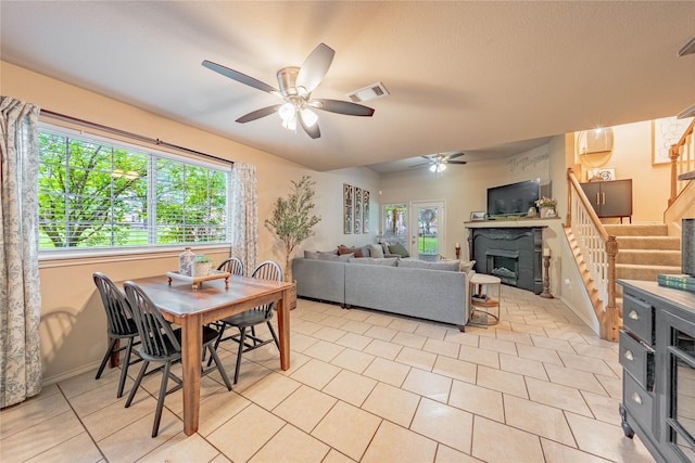 dining room featuring stairs, a ceiling fan, baseboards, a fireplace, and light tile patterned floors