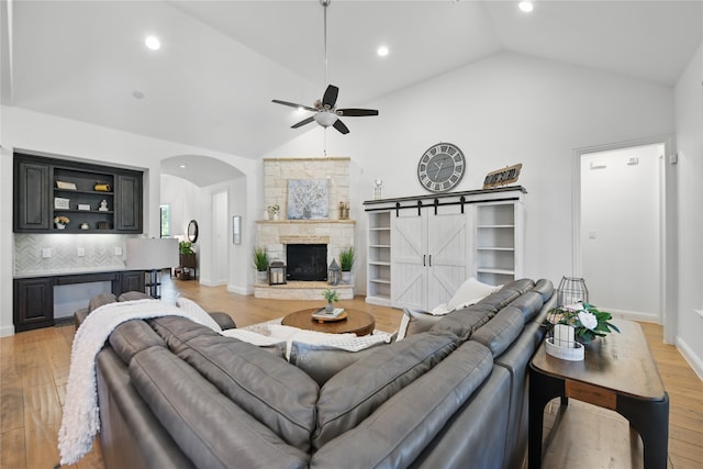 living room with light wood finished floors, a ceiling fan, arched walkways, recessed lighting, and a barn door
