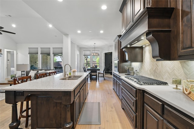 kitchen featuring a sink, stainless steel appliances, tasteful backsplash, a kitchen island with sink, and a kitchen bar