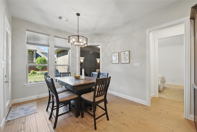 dining room featuring light wood finished floors, a chandelier, and baseboards