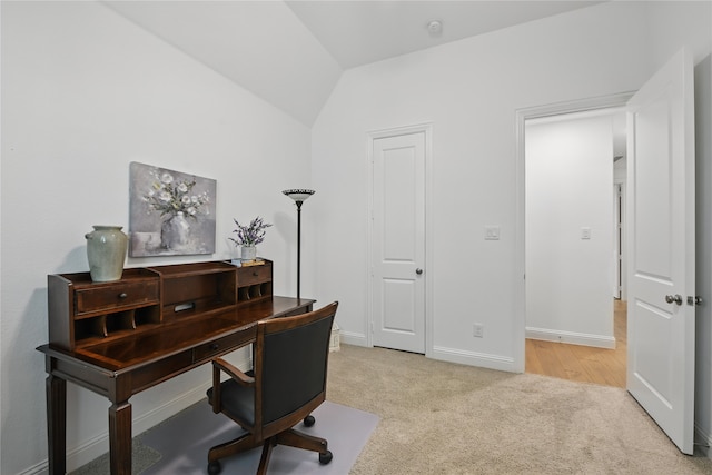 home office with light carpet, vaulted ceiling, and baseboards