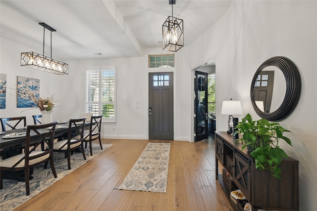 foyer entrance with hardwood / wood-style floors, a chandelier, and baseboards