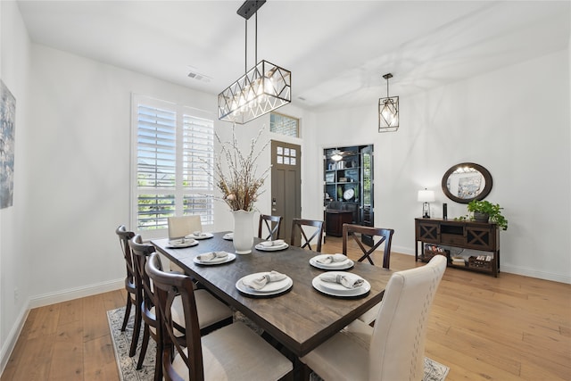dining room with light wood-style floors, plenty of natural light, baseboards, and a chandelier