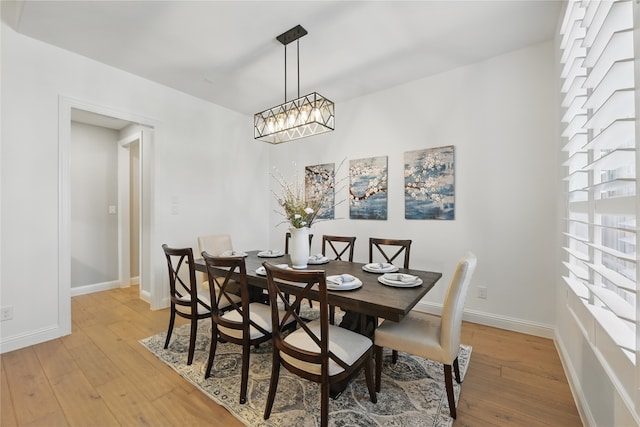 dining area with light wood finished floors, baseboards, and a chandelier