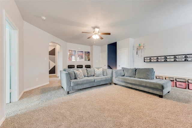 carpeted living room with arched walkways, ceiling fan, and baseboards