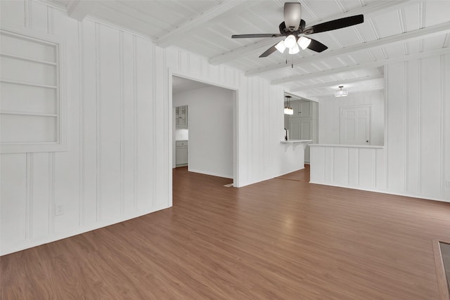 1501 W Day St, Denison, TX 75020 - unfurnished living room featuring ceiling fan, wood finished floors, beam ceiling, built in shelves, and a decorative wall