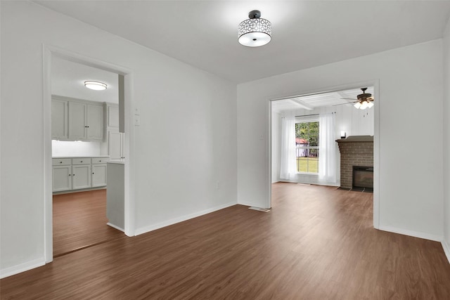 1501 W Day St, Denison, TX 75020 - unfurnished living room with dark wood-style flooring, baseboards, a ceiling fan, and a fireplace