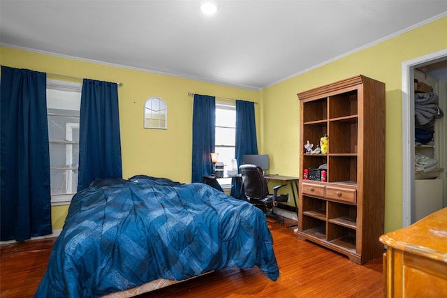 bedroom with wood finished floors, ornamental molding, and a desk