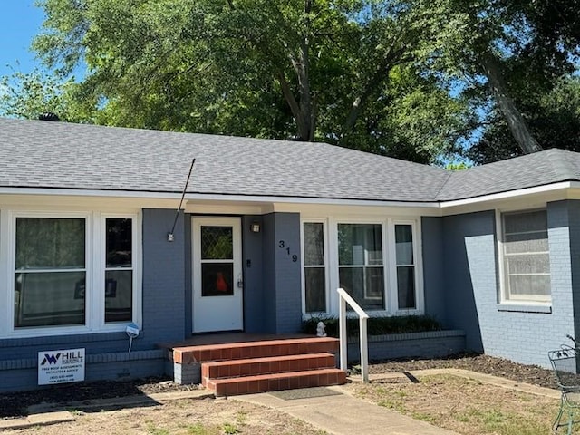 view of front facade with a shingled roof and brick siding