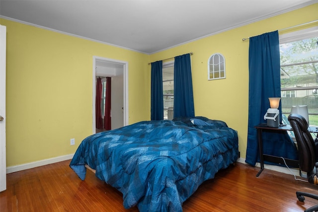 bedroom featuring wood finished floors, ornamental molding, and baseboards