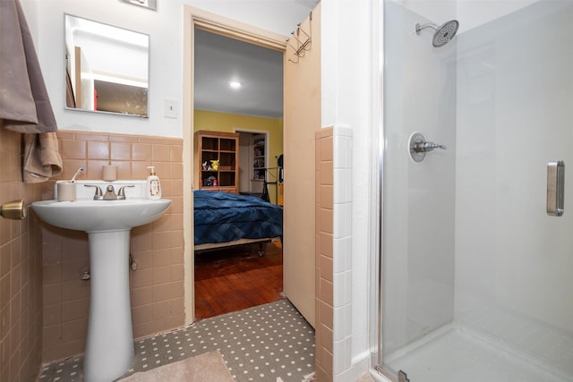 full bath with a stall shower, a sink, and tile walls