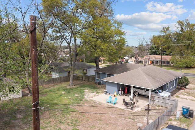 back of house featuring a patio area, a fenced backyard, roof with shingles, a residential view, and driveway