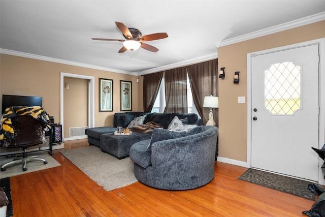 living area with wood finished floors, ceiling fan, crown molding, and baseboards