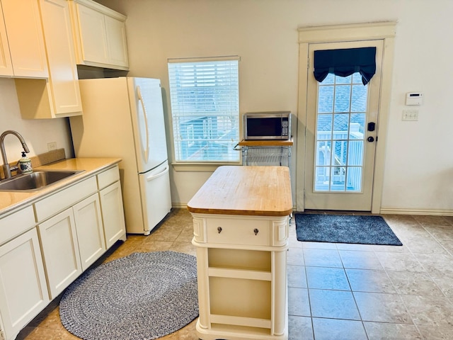 7501 Darrow Dr, Mckinney, TX 75071 - kitchen featuring a sink, stainless steel microwave, butcher block counters, white cabinets, and freestanding refrigerator