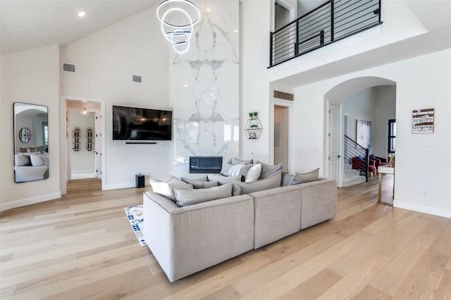 3228 Saddle Brook Rd, Celina, TX 75009 - living room featuring high vaulted ceiling, arched walkways, light wood finished floors, baseboards, and stairs